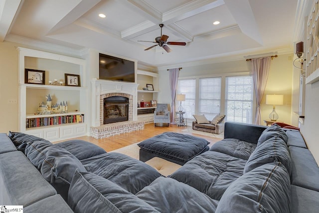 living room with coffered ceiling, crown molding, built in features, hardwood / wood-style flooring, and a fireplace