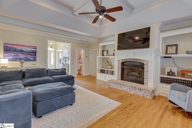 living room with ornamental molding, light hardwood / wood-style flooring, built in features, and a fireplace