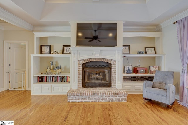 unfurnished room with crown molding, hardwood / wood-style flooring, built in features, ceiling fan, and a brick fireplace