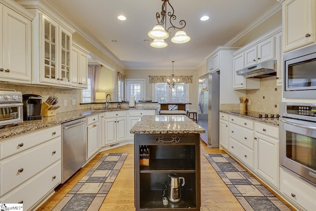 kitchen featuring sink, a center island, hanging light fixtures, a notable chandelier, and stainless steel appliances