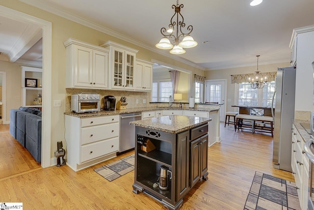 kitchen with sink, an inviting chandelier, a center island, hanging light fixtures, and appliances with stainless steel finishes