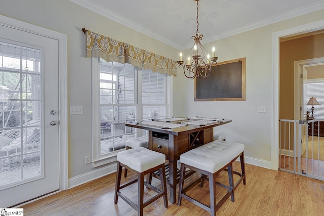 dining space with ornamental molding, a notable chandelier, and light hardwood / wood-style flooring