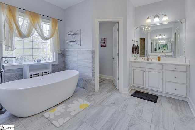 bathroom featuring vanity, a tub to relax in, and tile walls