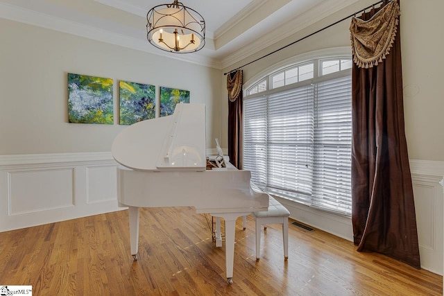 miscellaneous room with a tray ceiling, a wealth of natural light, ornamental molding, and light wood-type flooring