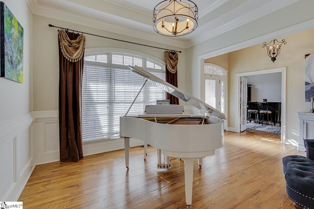 interior space featuring crown molding, a tray ceiling, an inviting chandelier, and light hardwood / wood-style flooring