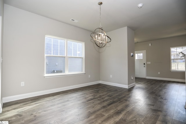 spare room featuring a notable chandelier and dark hardwood / wood-style flooring