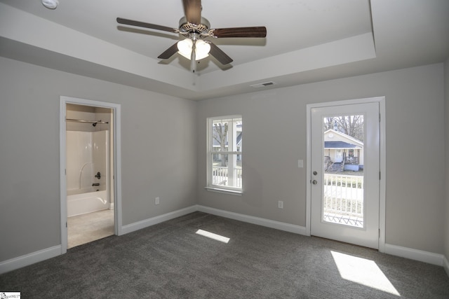 interior space featuring ceiling fan, plenty of natural light, and a tray ceiling