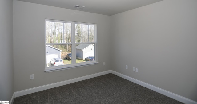 spare room featuring plenty of natural light and dark colored carpet