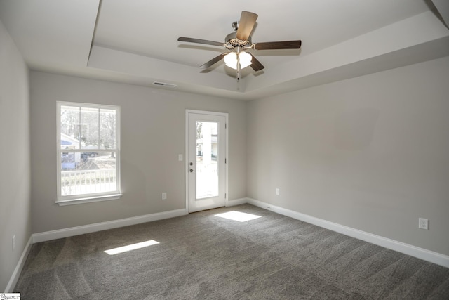 carpeted spare room featuring a raised ceiling and ceiling fan