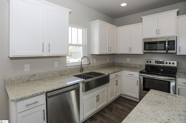 kitchen with sink, white cabinetry, stainless steel appliances, dark hardwood / wood-style floors, and light stone counters