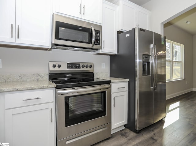 kitchen with white cabinetry, light stone counters, dark hardwood / wood-style floors, and appliances with stainless steel finishes