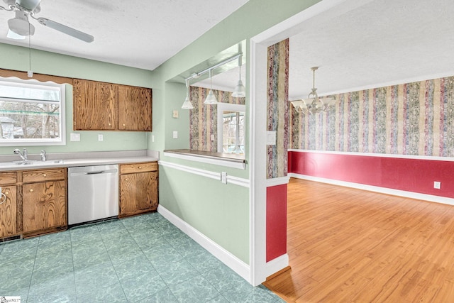 kitchen with ceiling fan with notable chandelier, pendant lighting, dishwasher, sink, and a textured ceiling