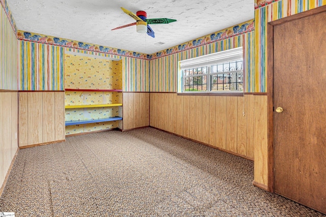 carpeted spare room with ceiling fan and a textured ceiling