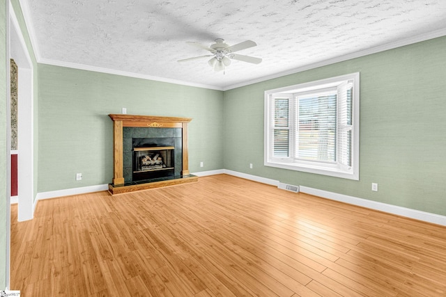 unfurnished living room with crown molding, ceiling fan, a fireplace, and light hardwood / wood-style floors