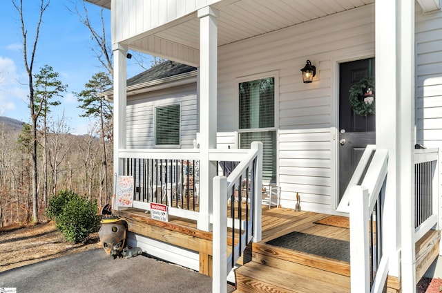 property entrance with covered porch and a shingled roof