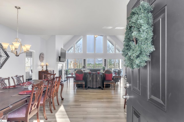 dining room with plenty of natural light, a chandelier, high vaulted ceiling, and light wood-type flooring