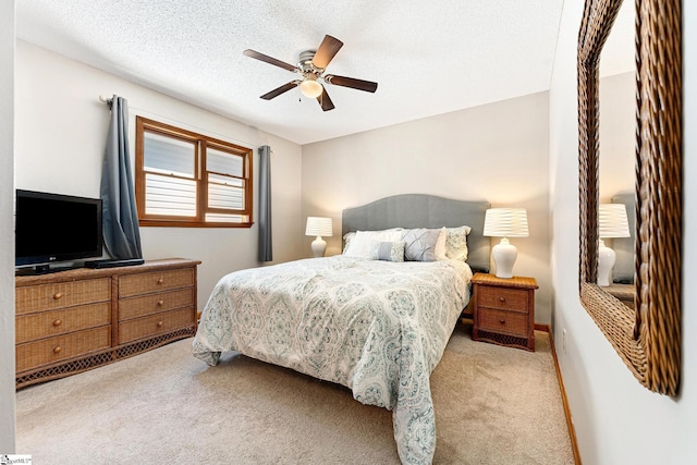 bedroom with ceiling fan, light colored carpet, and a textured ceiling