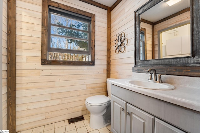 bathroom featuring tile patterned floors, toilet, vanity, and wood walls