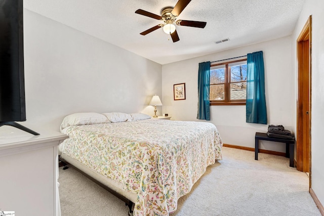 carpeted bedroom featuring ceiling fan and a textured ceiling