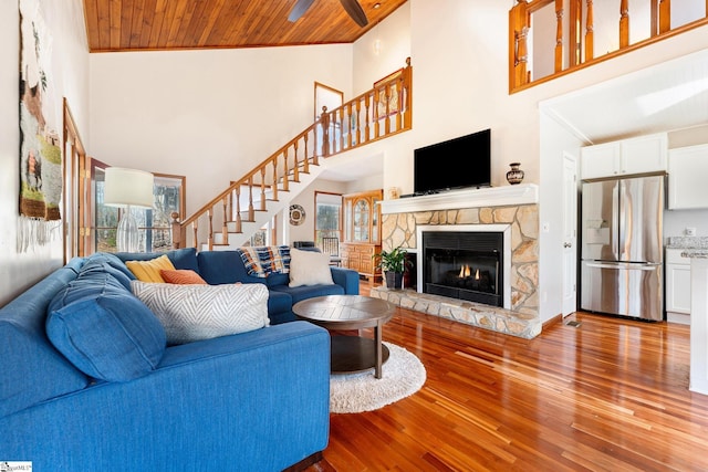 living room with wood ceiling, a fireplace, a high ceiling, and hardwood / wood-style flooring