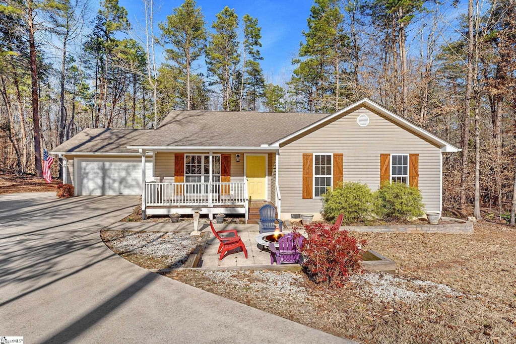 single story home with a fire pit, a garage, and covered porch