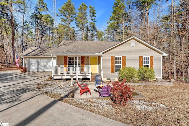 single story home with a fire pit, a garage, and covered porch