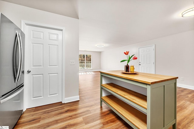 kitchen featuring stainless steel fridge, wooden counters, wood-type flooring, and green cabinets