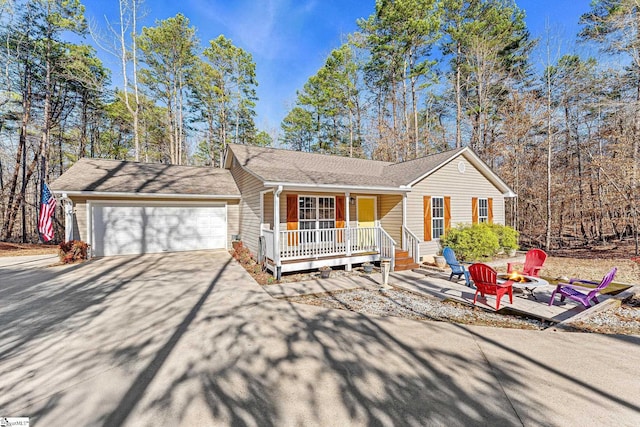 single story home featuring a porch, a garage, and an outdoor fire pit