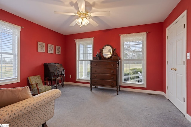 living area with light carpet and ceiling fan