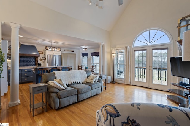 living room featuring decorative columns, high vaulted ceiling, track lighting, ceiling fan, and light hardwood / wood-style floors