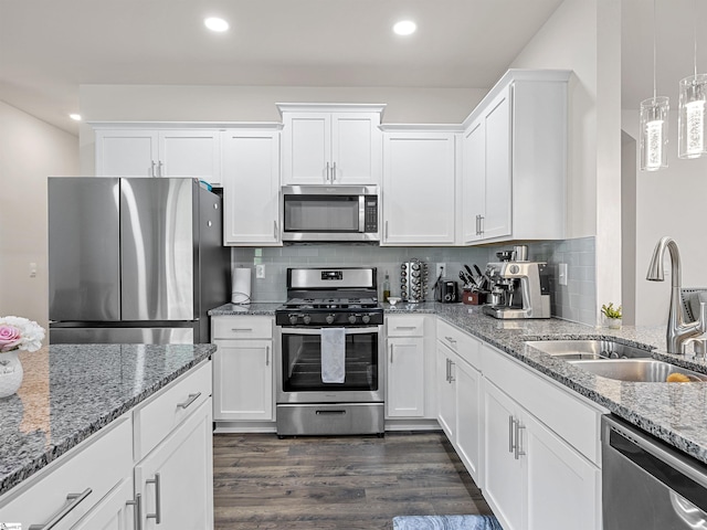 kitchen with white cabinets, dark wood-style floors, appliances with stainless steel finishes, pendant lighting, and a sink