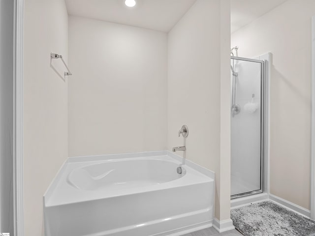 bathroom featuring a stall shower, baseboards, and a bath