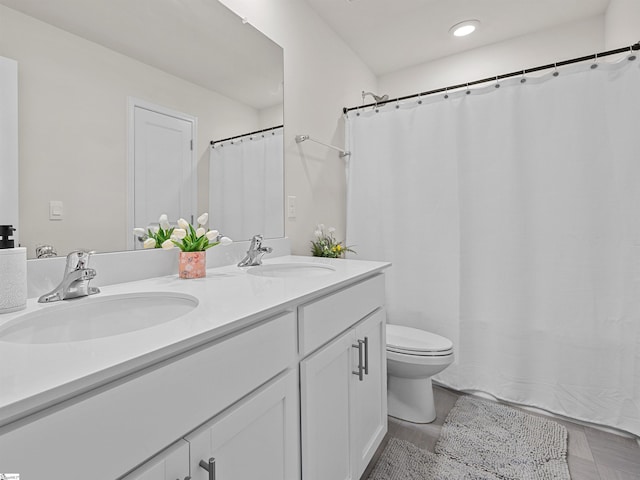 bathroom with double vanity, toilet, and a sink