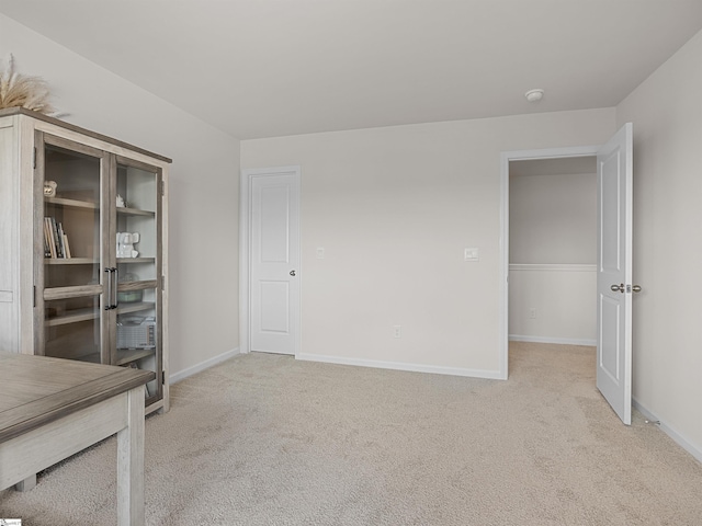 unfurnished room featuring light carpet and baseboards