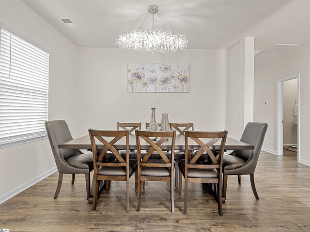 dining room featuring baseboards, wood finished floors, visible vents, and an inviting chandelier