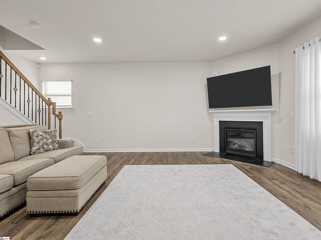 living area featuring recessed lighting, stairway, dark wood finished floors, and a glass covered fireplace