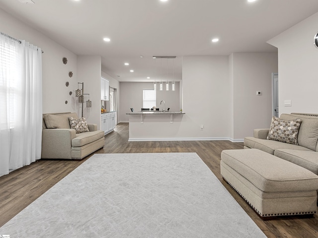 living area with dark wood-type flooring, recessed lighting, and a healthy amount of sunlight