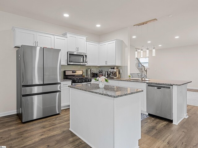 kitchen with a sink, white cabinetry, appliances with stainless steel finishes, a center island, and pendant lighting