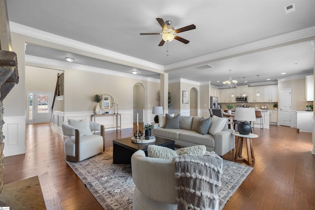 living room with ornamental molding, dark hardwood / wood-style flooring, and ceiling fan with notable chandelier