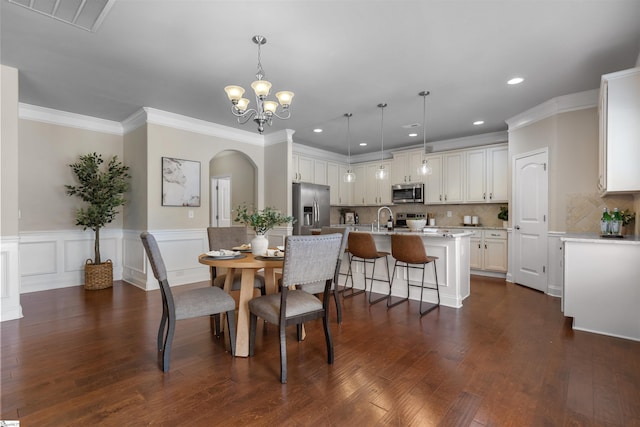 dining space featuring dark wood-type flooring, ornamental molding, a chandelier, and sink