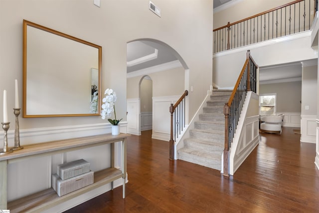 foyer entrance featuring dark hardwood / wood-style flooring, a towering ceiling, and ornamental molding