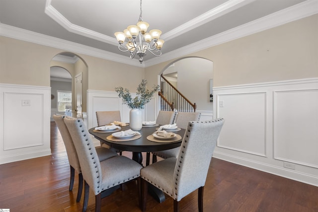 dining room with crown molding, a tray ceiling, dark hardwood / wood-style floors, and a chandelier