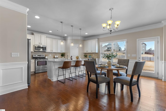 dining room with sink, crown molding, dark hardwood / wood-style floors, and a chandelier