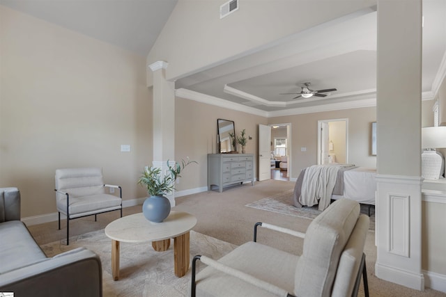 bedroom featuring decorative columns, ornamental molding, light colored carpet, a tray ceiling, and ensuite bath