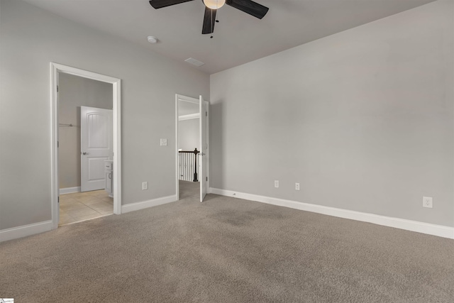 unfurnished bedroom featuring ensuite bathroom, light colored carpet, and ceiling fan