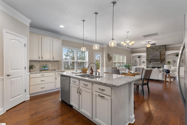 kitchen featuring sink, light stone counters, decorative light fixtures, dishwasher, and a kitchen island with sink