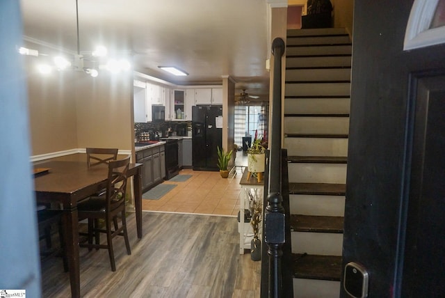 interior space with ceiling fan, white cabinetry, hardwood / wood-style floors, tasteful backsplash, and black appliances