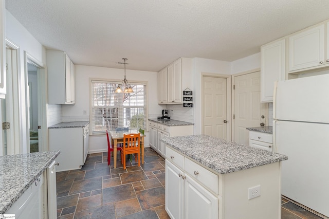 kitchen with white cabinetry, decorative light fixtures, a center island, and white fridge