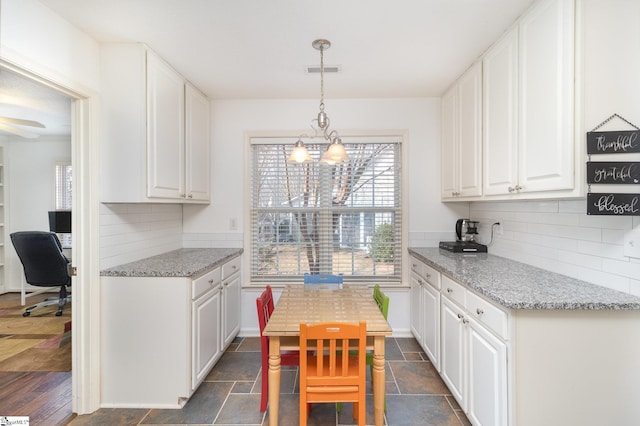 kitchen with pendant lighting, light stone counters, and white cabinets