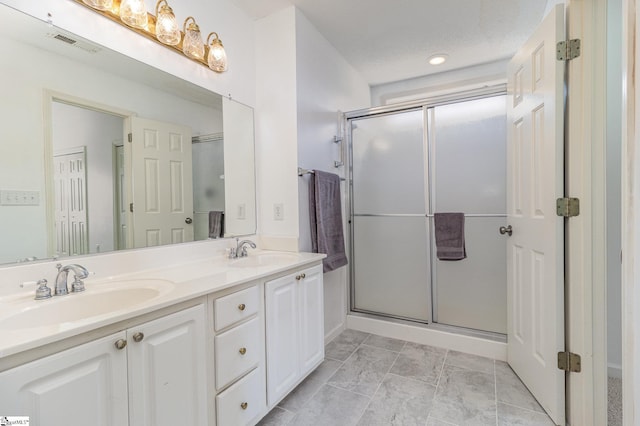 bathroom featuring vanity, a textured ceiling, and a shower with shower door